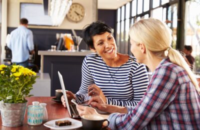 Two women talking to each in a cafe.