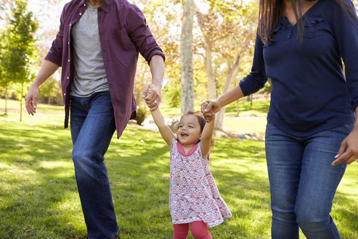 Mixed race couple lifting young daughter in park, crop shot