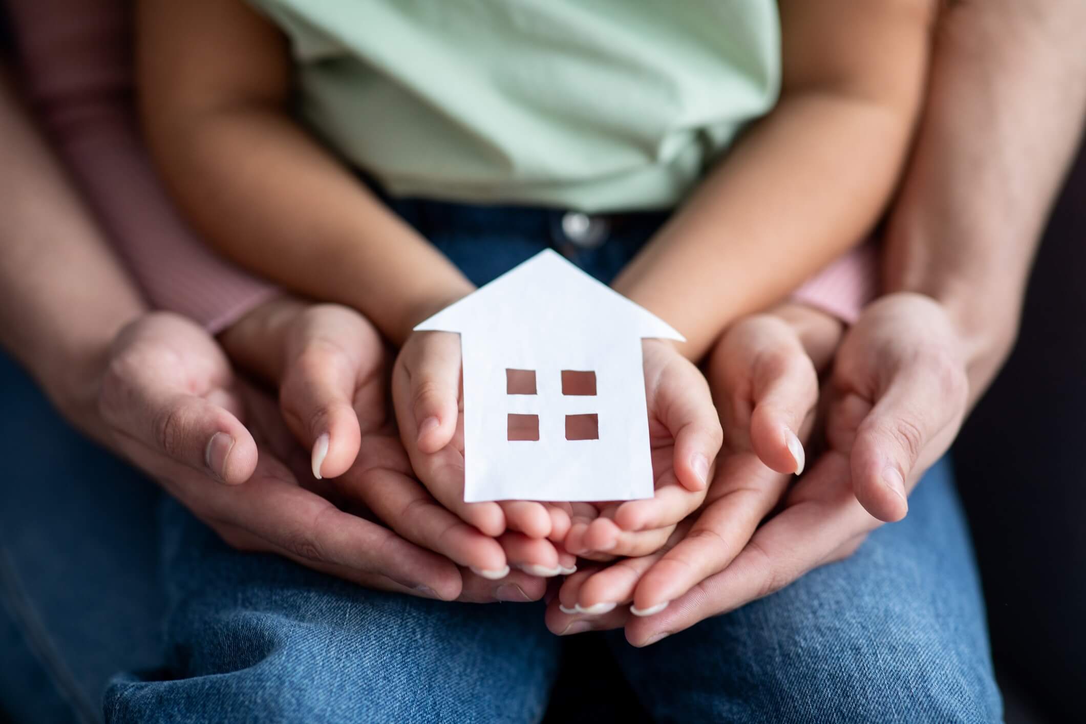 A family hold a paper cut out of a house in their hands.