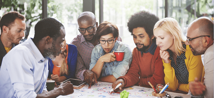 Group of diverse individuals around paper