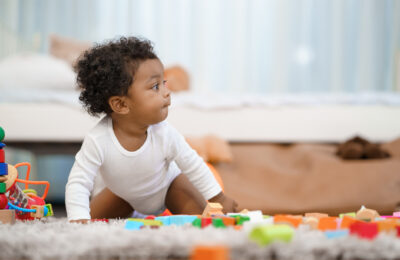 Infant crawling amongst toys in bedroom