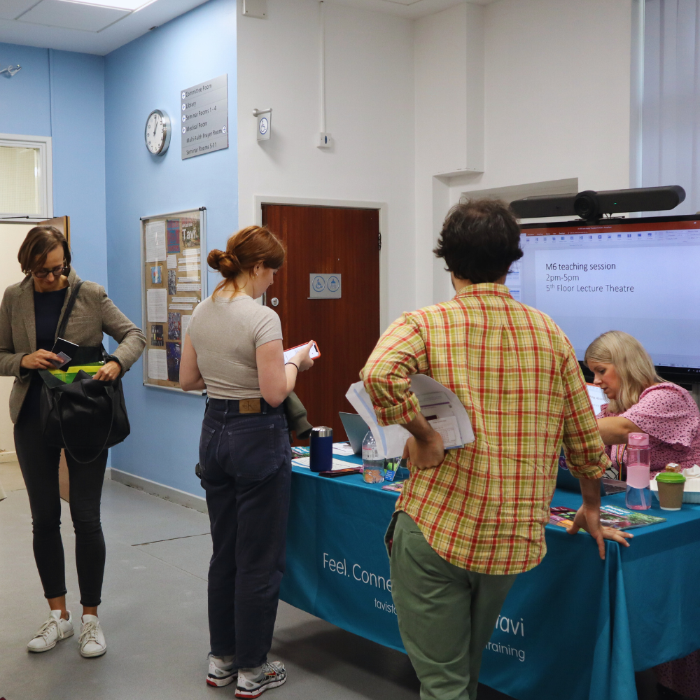 Three new students collecting their welcome packs. 