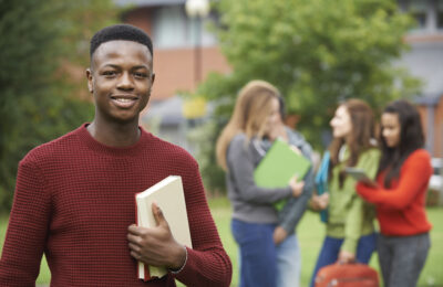 A smiling teenager standing in front of a group of other teenagers