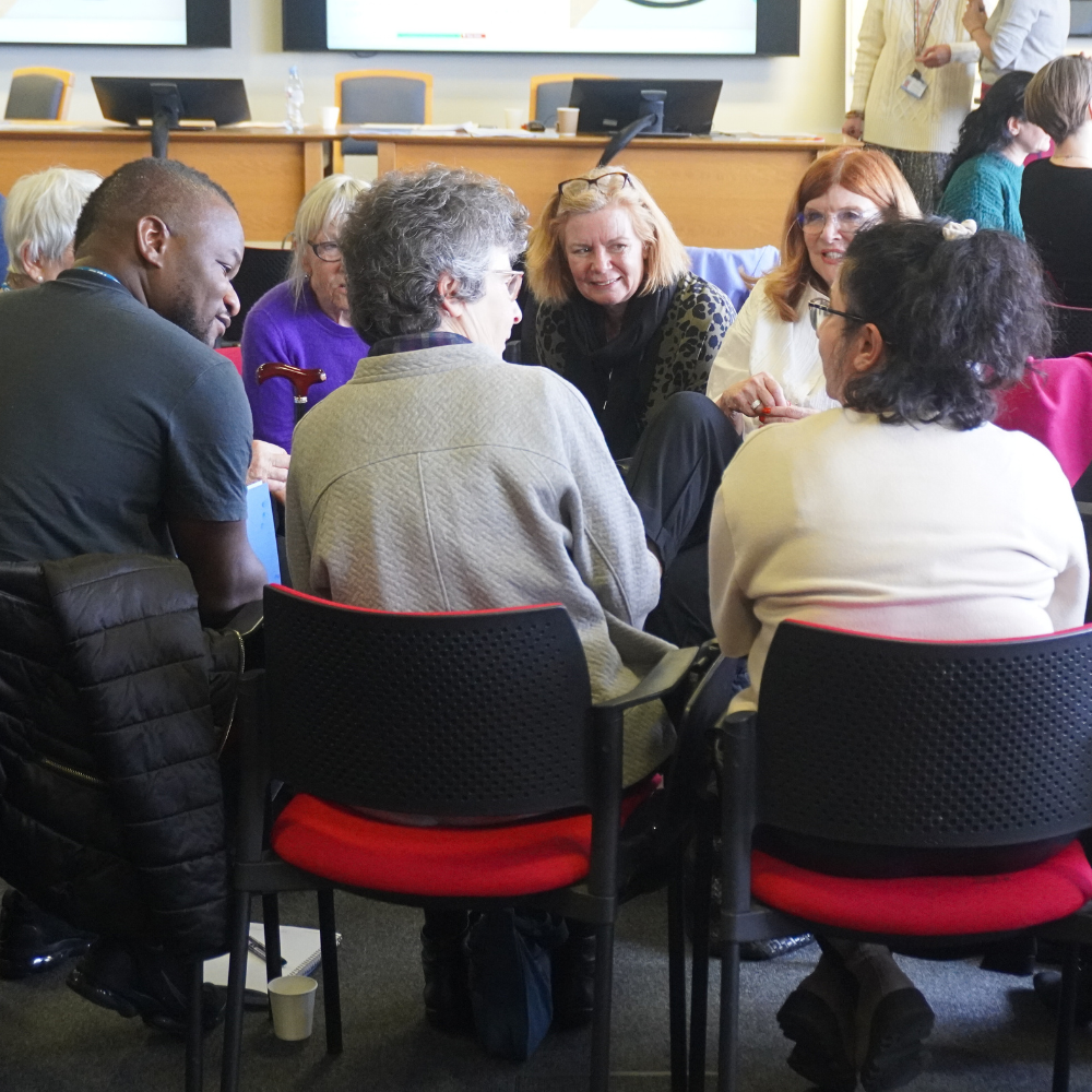Group discussion at the 2024 Infant observation conference. Delegates are sat in red chairs that form a circle.