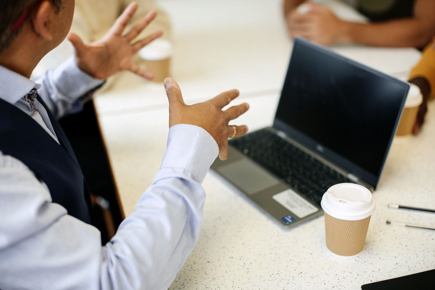 Person gesturing while working at laptop