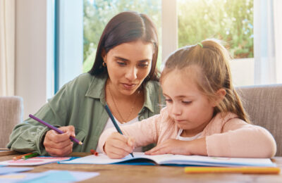 A woman supporting a young child with homework
