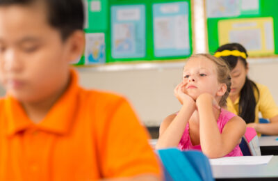 A young student looking bored in the classroom.