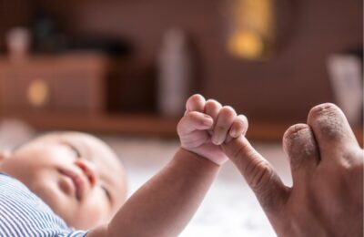 A baby holding a woman's hand