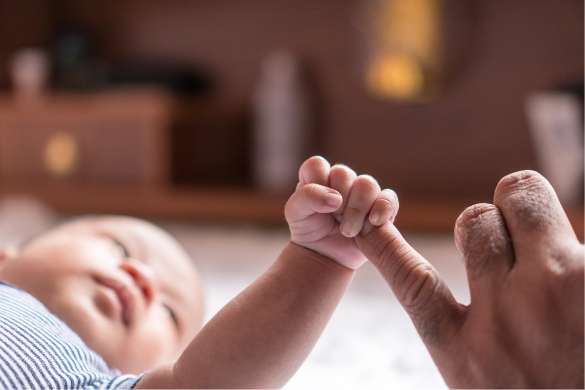 A baby holding a woman's hand