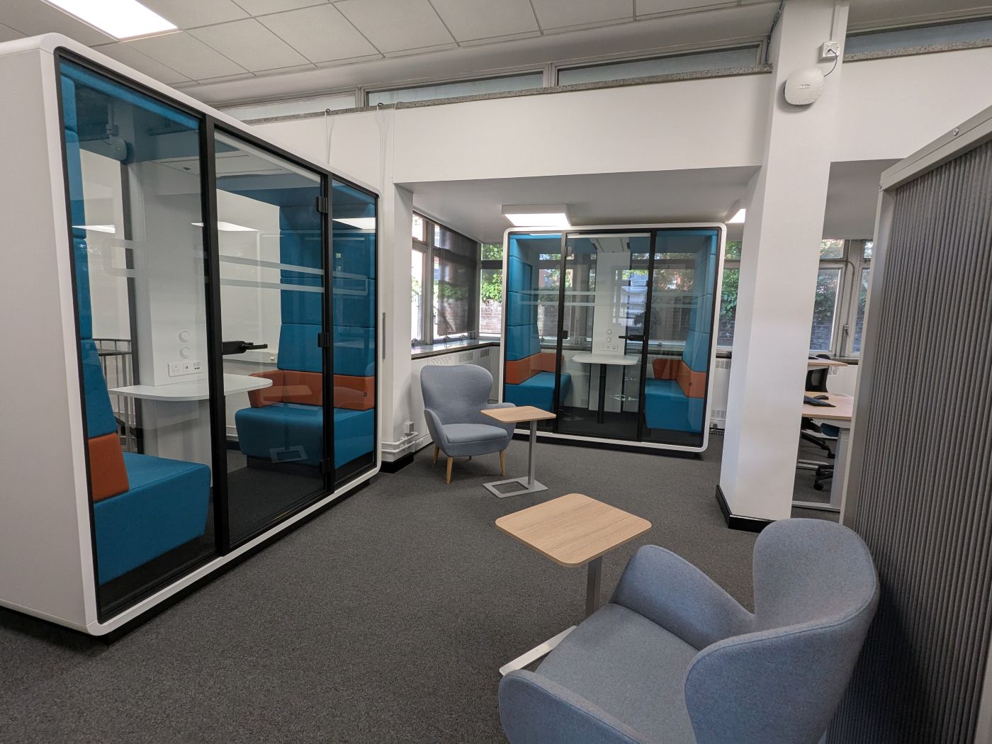 Two group study pods with armchairs outside them, at the rear of the Tavistock Centre library
