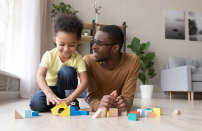 A father and daughter sat on the floor playing with toys.